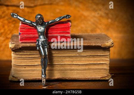 Silver crucifix without the cross and two Holy Bibles on a wooden table with dark shadows Stock Photo