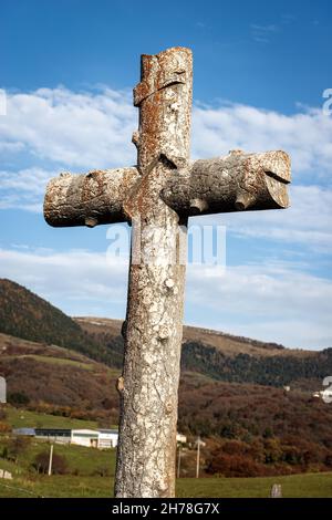 Ancient christian cross made of stone in a rural scene (imitation of a tree trunk), near the small village of Sant'Anna d'Alfaedo, Lessinia plateau. Stock Photo