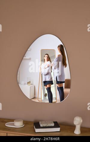 Reflection of young woman in wall mirror Stock Photo