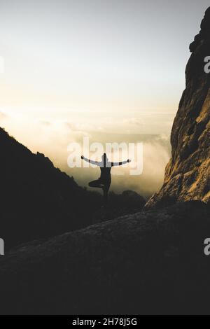 Silhouette of female doing tree pose yoga on the cliff. Woman ...