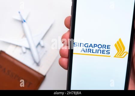 Singapore Airlines application on the screen of mobile phone in mans hand. Passport, boarding bass are next to a white plane on the background. November 2021, San Francisco, USA Stock Photo