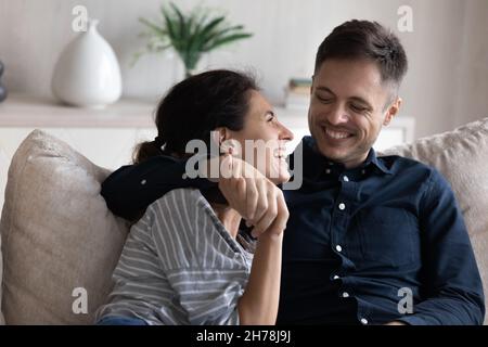 Young 30s peaceful couple hugging relaxing on sofa enjoy conversation Stock Photo