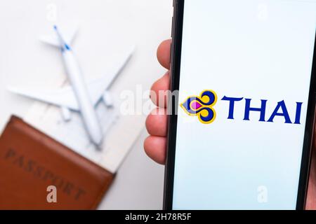 Thai Airline application on the smartphone screen mans handn. A white toy airplane and a passport are lying on a table with a light surface.November 2021, San Francisco, USA Stock Photo