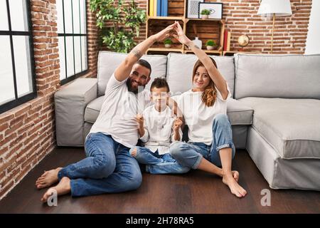 Family of three doing house shape with arms screaming proud, celebrating victory and success very excited with raised arm Stock Photo