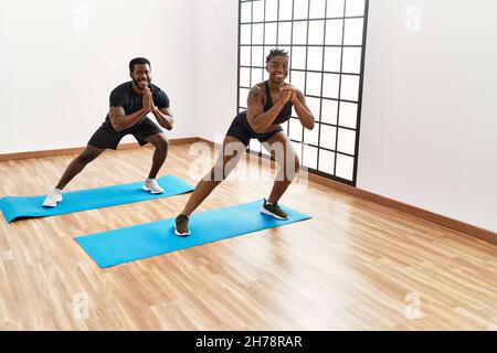 Young african american sporty couple smiling happy doing legs exercise at sport center. Stock Photo