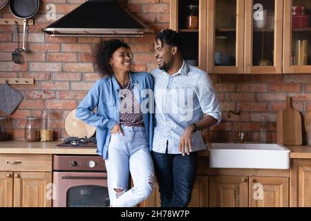 Happy young African American family couple talking in kitchen. Stock Photo