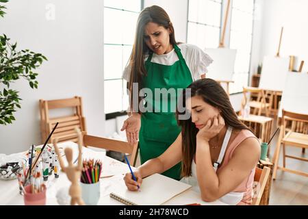 Two latin paint students arguing sitting on the table at art school. Stock Photo