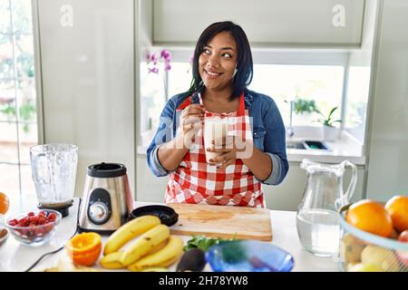 Hispanic brunette woman drinking fresh fruit smoothie at the kitchen Stock Photo