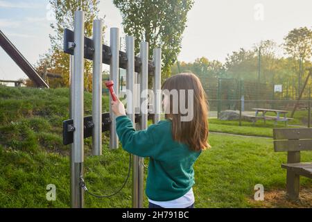 young girl with school unifome playing music on a xylophone in a playground Stock Photo