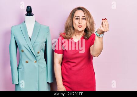 Middle age caucasian woman standing by manikin doing italian gesture with hand and fingers confident expression Stock Photo