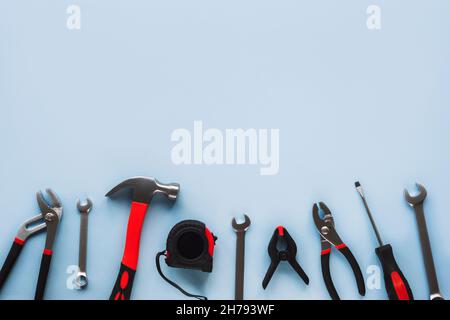 Working tools hammer, screwdriver, pliers, spanner and meter on light blue background, top view, flat lay. Copy space. Stock Photo