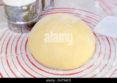 Raw yeast dough on the floured silicone baking mat with markings on the kitchen table. Stock Photo