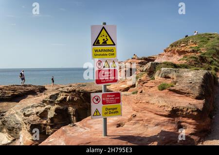 West Kirby, UK: Sign warning of unstable rock on cliff edge, Hilbre island on the Deeside estuary, Wirral peninsula. Stock Photo