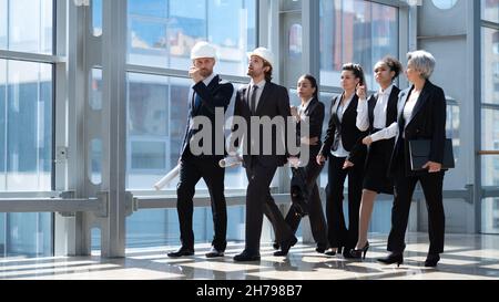 Team of construction industry workers engineer architect business people professionals walking together in modern lobby Stock Photo