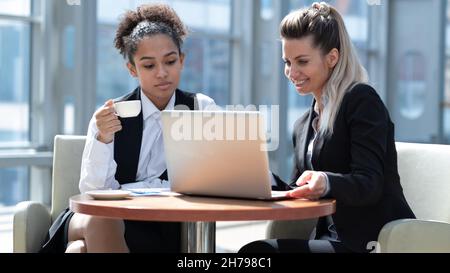 Two business women in modern office building cafe working with laptop Stock Photo