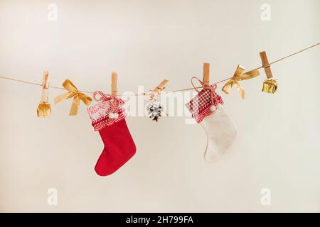 christmas socks with pine cone, golden presents and decorations on the rope on white background Stock Photo