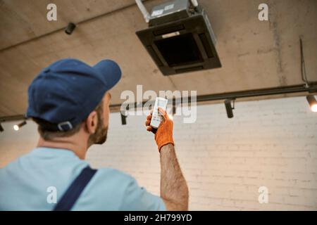 Male worker checking air conditioner in restaurant Stock Photo