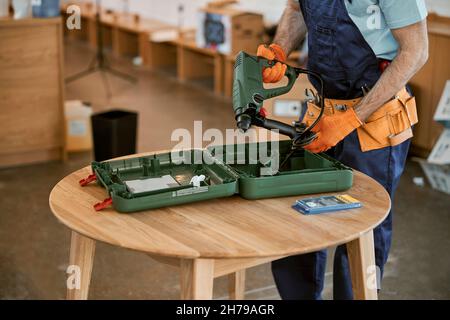 Male builder in gloves holding electric hammer drill Stock Photo