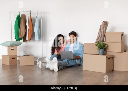 Happy millennial couple using laptop after relocation Stock Photo