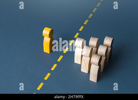 A person and a group of people are separated by a yellow line. Establishing contact. Distrust. Quarantine. Distance with strangers. Barrier to underst Stock Photo