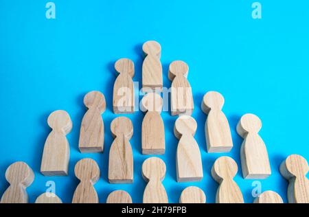 Wooden figures of people in one direction on a blue background. Social organizations, commercial structure. Organization, joining consolidated forces. Stock Photo
