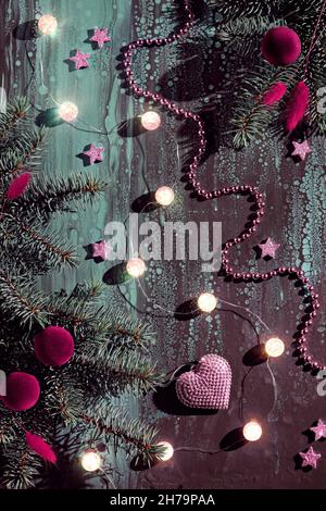 Pink donuts and other Christmas decorations on dark abstract background. Xmas lights , ball garland, pink stars and sparkling heart shape, fir twigs. Stock Photo