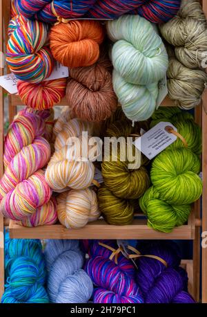 a selection of brightly coloured dyed skeins of wool on display at a wool and thread needlework shop, primary coloured wool skeind or balls of wool. Stock Photo