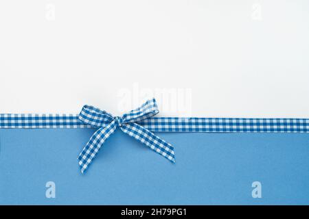 Plaid ribbon tied in a bow on white and blue background Stock Photo