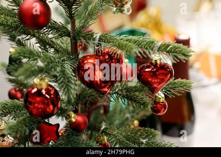 Small Christmas tree with red toys on a table with wine bottles. Festive decorations for New Year celebration Stock Photo