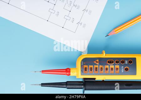 Two-pole voltage indicator with electrical drawings on a blue background. Testing and verification of electrical networks Stock Photo