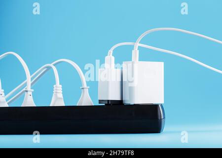 Surge protector with connected white wires of electrical appliances on a blue background. Free space Stock Photo