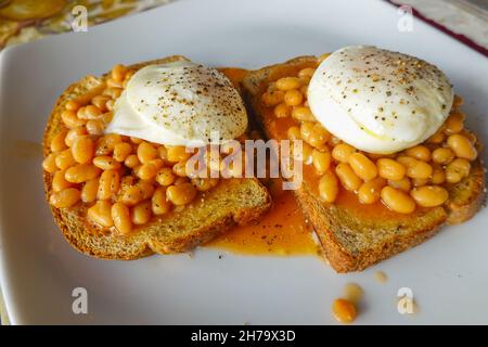 British family breakfast of poached eggs on top of baked beans on toast. Stock Photo