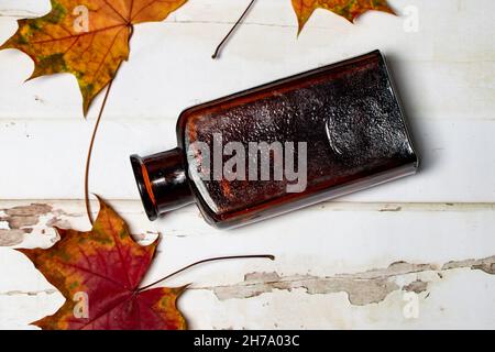 Antique Brown Glass Medicine Bottle with Autumn Leaves Lay Flat Stock Photo