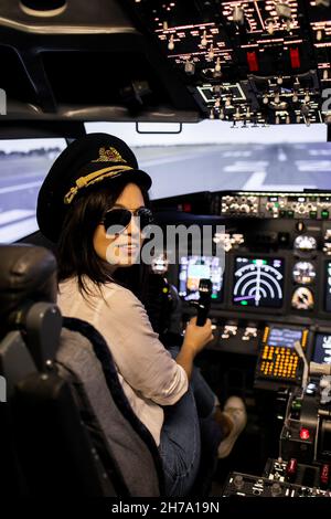 Female Pilot in the Airplane Cockpit. Pilot wearing sun glasses and hat Stock Photo