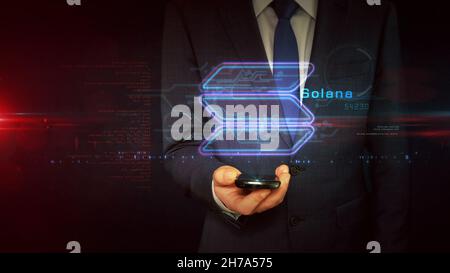 Solana sign concept, SOL cryptocurrency token, blockchain currency, fintech and business technology. Businessman touch the hologram display in hand. F Stock Photo