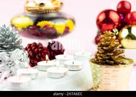 Various Tealight Candles Illuminated In Row With Flower Pine Cone Glitter Decorations On Light Pink Background. Theme For Merry Christmas And Happy Ne Stock Photo