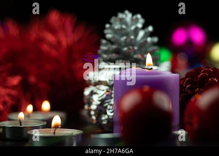 Designer Purple Or Lilac Pillar Candle Illuminated With Christmas Ornaments Like Pine Cone Cherries Baubles And Red Fur In Background. Theme For Merry Stock Photo