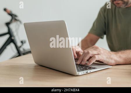Telecommuter typing laptop computer keyboard in home office while performing remote work task, selective focus Stock Photo