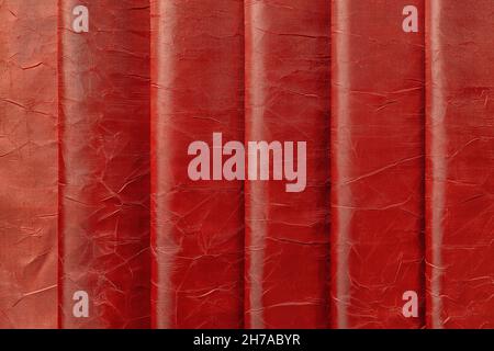 Shiny red wrinkled silk vertical folds background. Texture of draped brick red color shiny satin cloth. Design element of elegant luxury crumpled silk Stock Photo