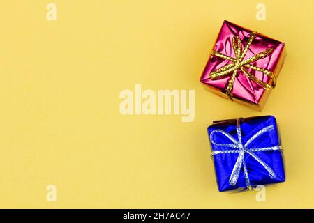 Box with gift on a yellow background with copy space for text. Red and blue boxes with gifts. Christmas gift boxes. Holidays Gifting. New Year gift Stock Photo