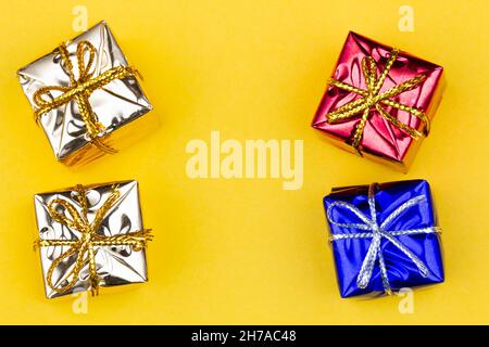 Box with gift on a yellow background with copy space for text. Golden, red, blue boxes with gifts. Christmas gift boxes. Holidays Gifting. New Year Stock Photo
