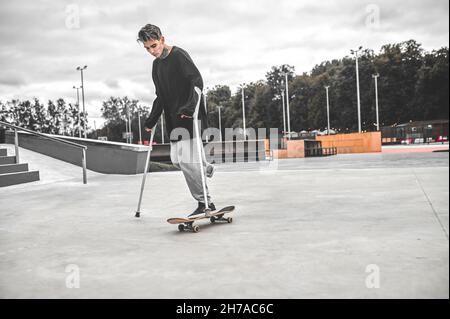 Disabled guy riding skateboard in park Stock Photo