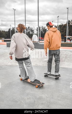 Two skateboarders riding skateboards with their backs to camera Stock Photo