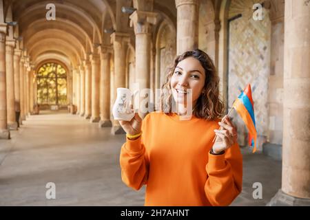Happy woman with Armenian flag drinking mineral hot water in the famous healing spring in the resort town of Jermuk in Armenia Stock Photo