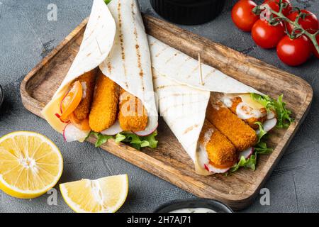 Sandwich roll with fish fingers, cheese and vegetables set, on wooden tray, on gray background Stock Photo