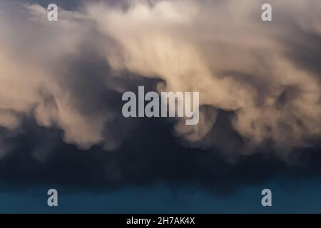 Unusual mammatus and cumulus clouds at dramatic sunset sky Stock Photo