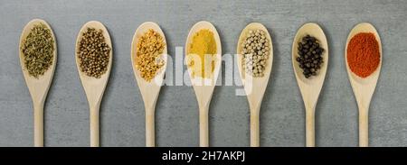 Various spices in wooden spoons side by side seen from above Stock Photo