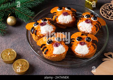 Tiger Sandwiches for New Year 2022 of salted herring, carrot and black olives on white bread on brown background, Close-up Stock Photo