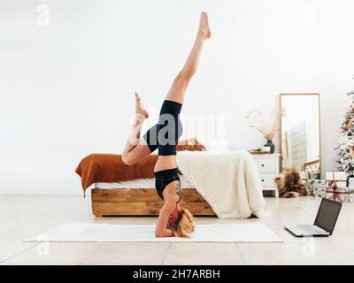 Young fit woman doing headstand exercise at home. Stock Photo
