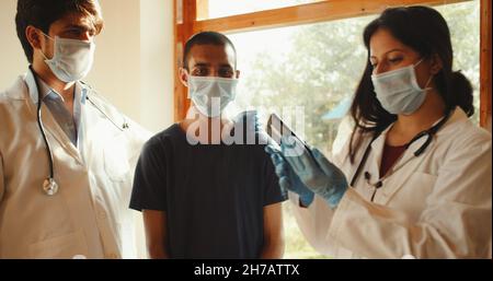 A doctor, nurse, and client wearing medical masks in a hospital Stock Photo